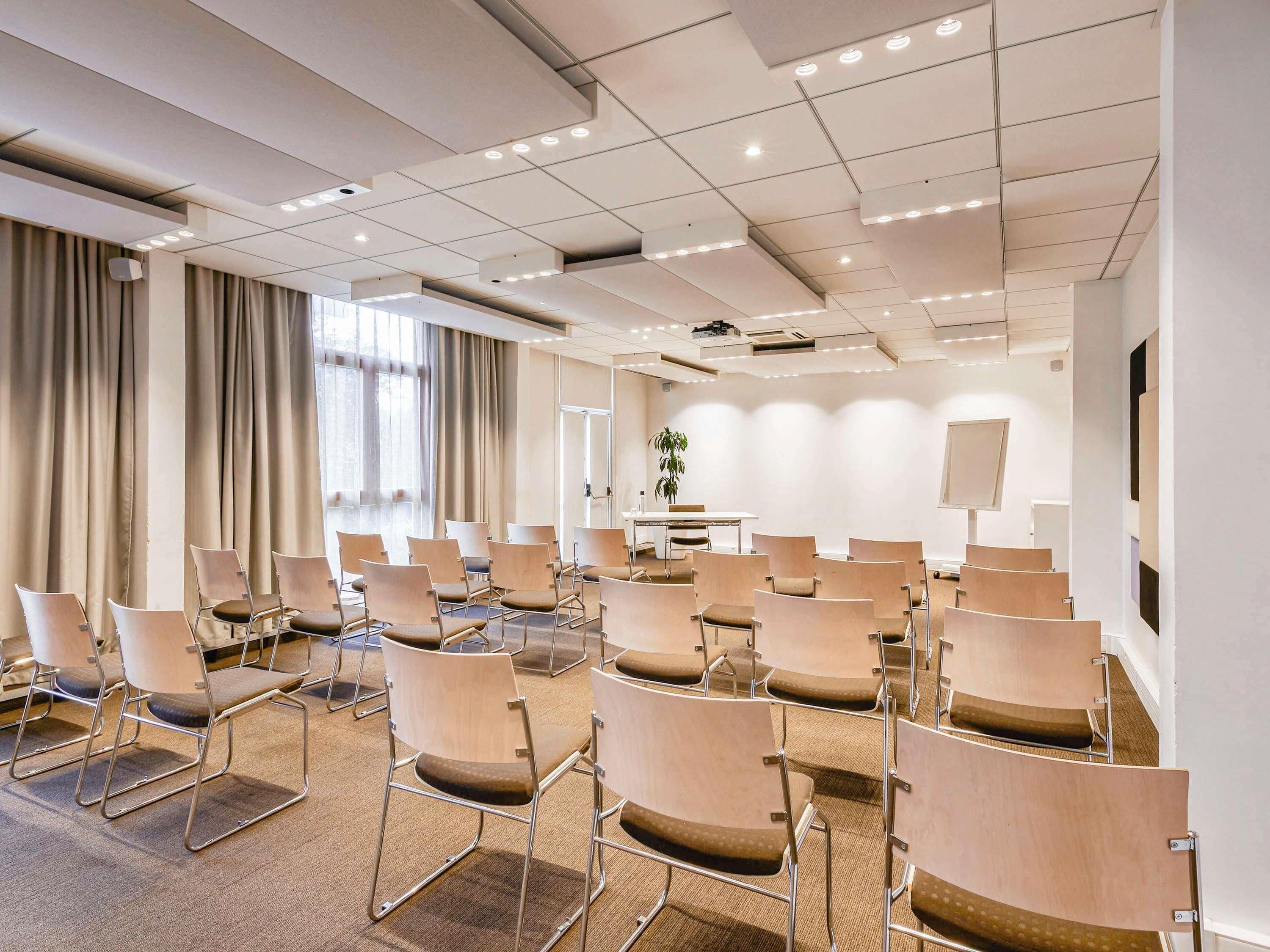 A conference room with rows of chairs, a projector, and a large screen.