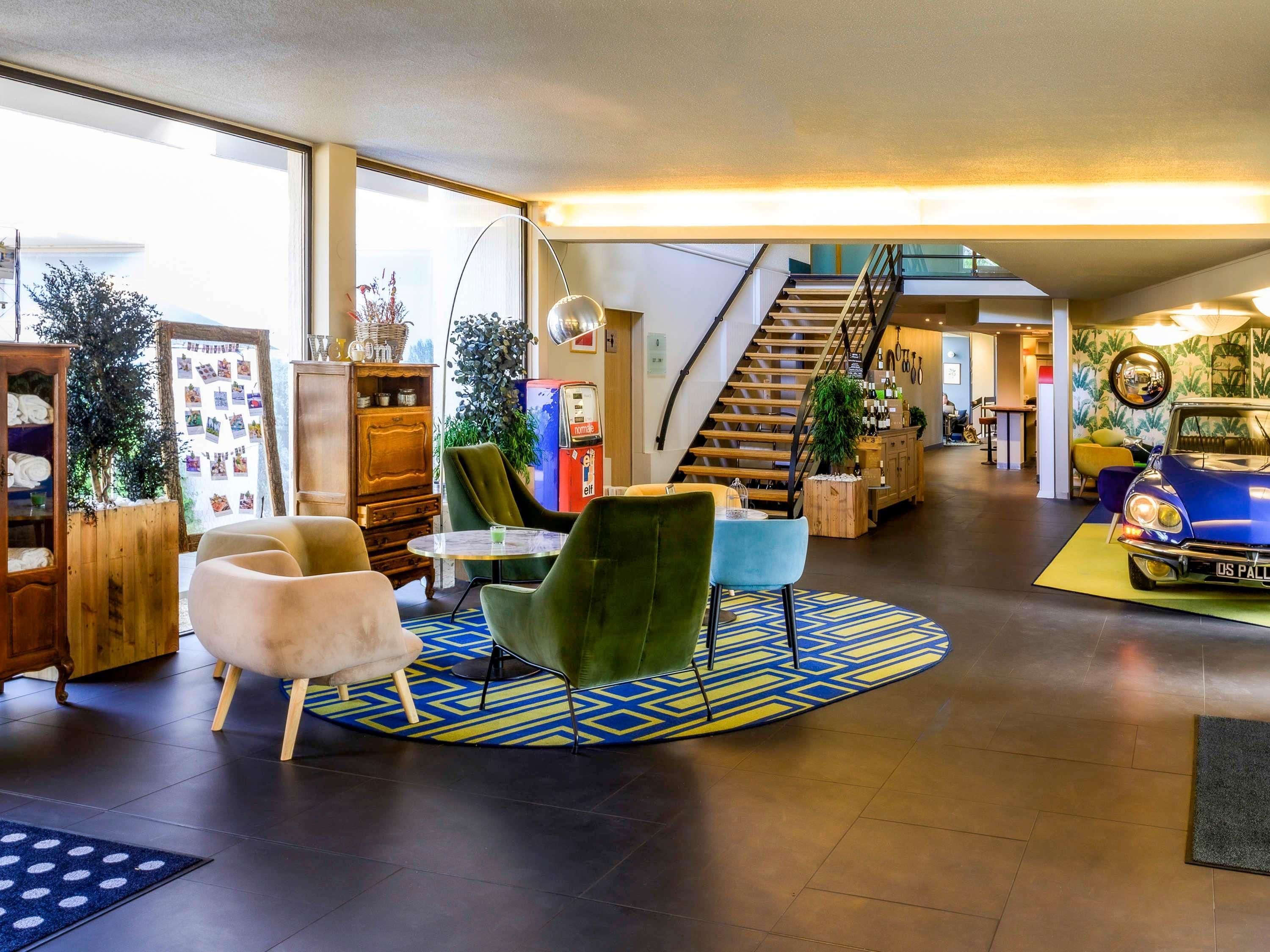 A spacious lobby with a staircase, modern furniture, and a vintage car display.