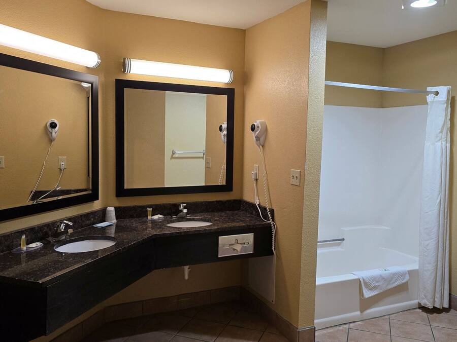 A bathroom with two sinks, a mirror, a hairdryer, and a shower.