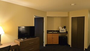 A compact hotel room with a television, a small kitchenette, and a wooden cabinet. - Haven Hotel (Shawano)