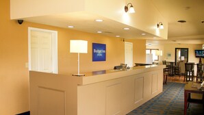 A reception desk with a sign reading "Budget Inn & Suites," a white door, and a blue patterned carpet.