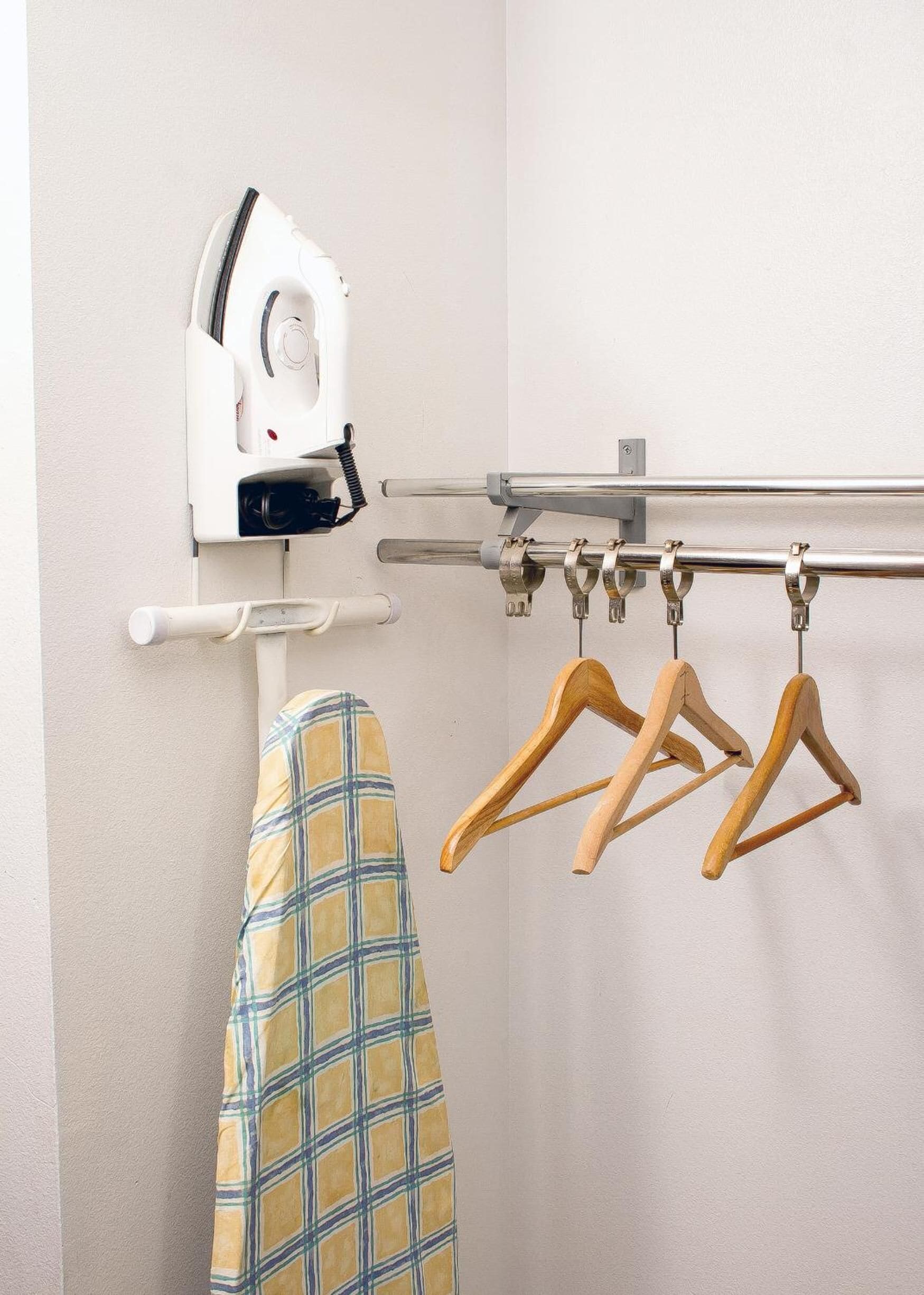A wall-mounted drying rack with a hanging iron and a folded garment.