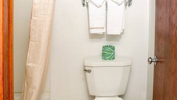 A bathroom with a toilet, a towel rack, and a shower curtain.