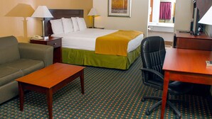 A hotel room with a bed, a desk, a chair, a sofa, and two lamps.