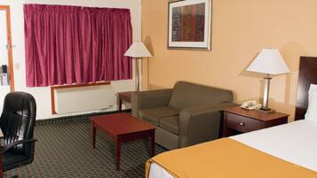 A hotel room with a bed, a chair, a desk, a lamp, and a painting on the wall.
