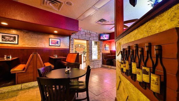 A restaurant interior with booths, a bar area, and a wall displaying wine bottles.