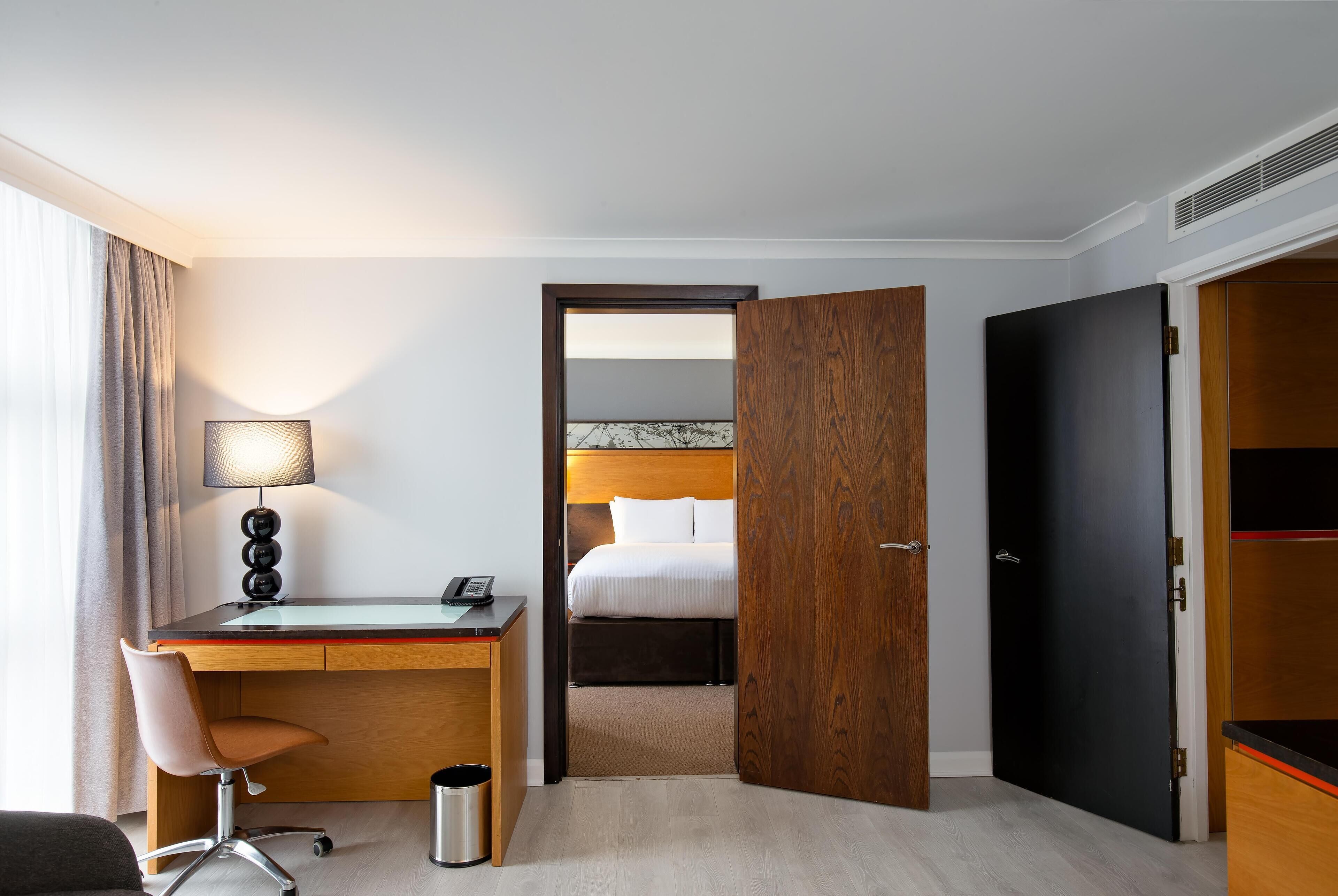 Ein Hotelzimmer mit einem Holztisch, einem Stuhl, einem Bett und einem Kleiderschrank.
