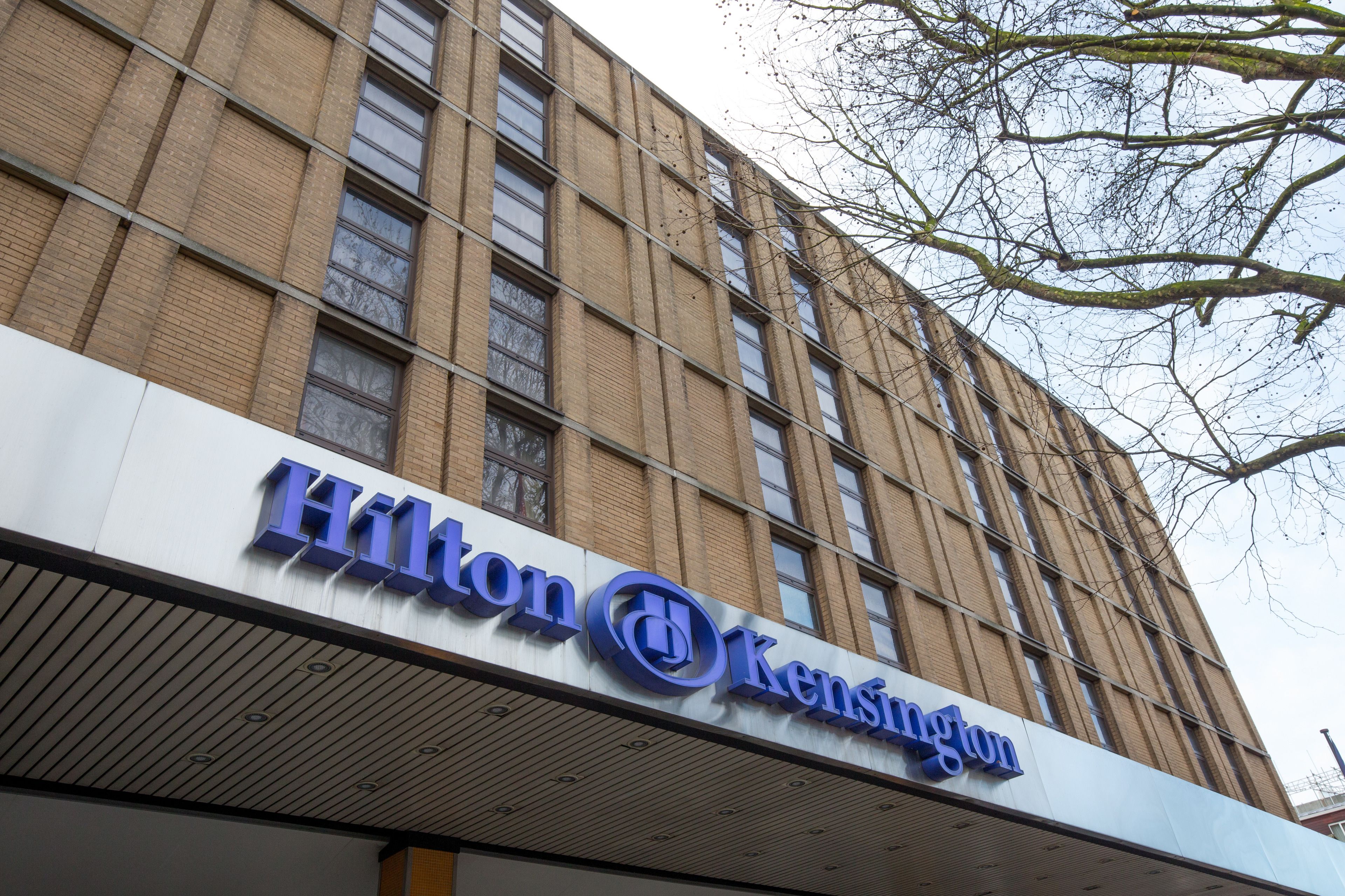 Un cartel de hotel Hilton con un diseño moderno, que muestra los logotipos de Hilton y Kensington.