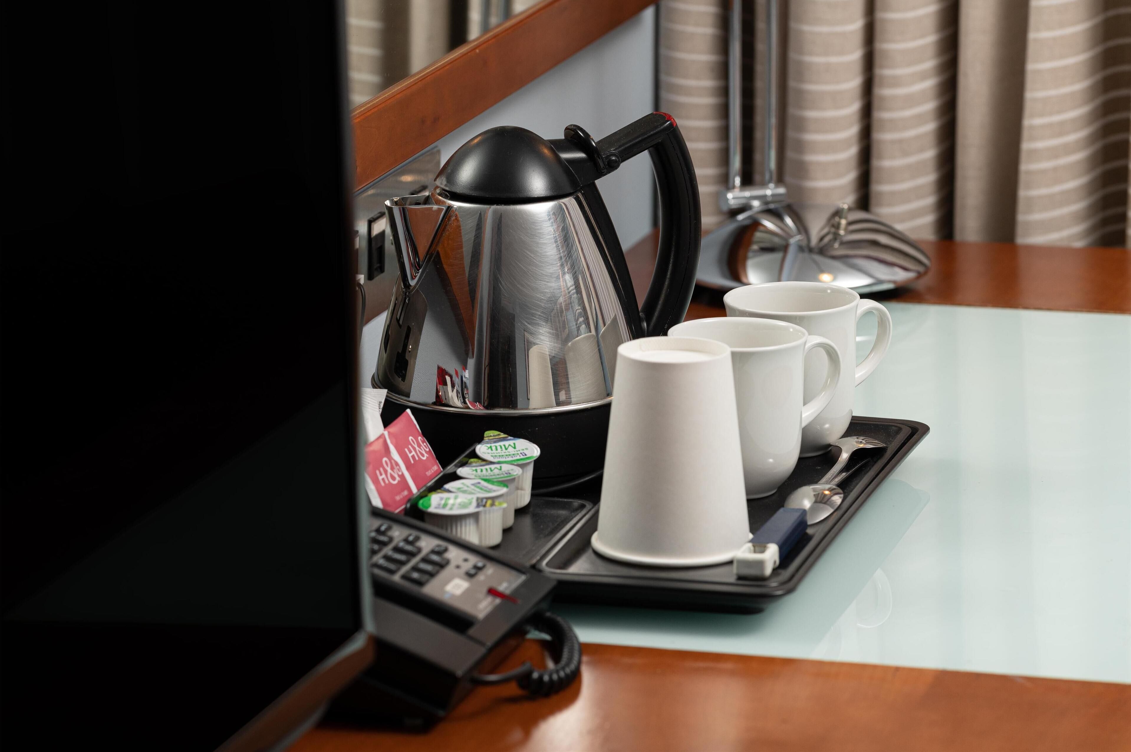 Ein Tablett mit Kaffeekanne, Tassen und Beilagen auf einem Tisch im Hotel.