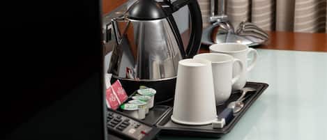 A tray with a coffee pot, cups, and condiments on a hotel table.