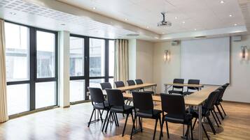 A conference room with a long table, black chairs, and a projector screen.
