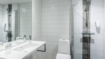 A modern bathroom with a large mirror, a sink, a toilet, and a glass-enclosed shower area.