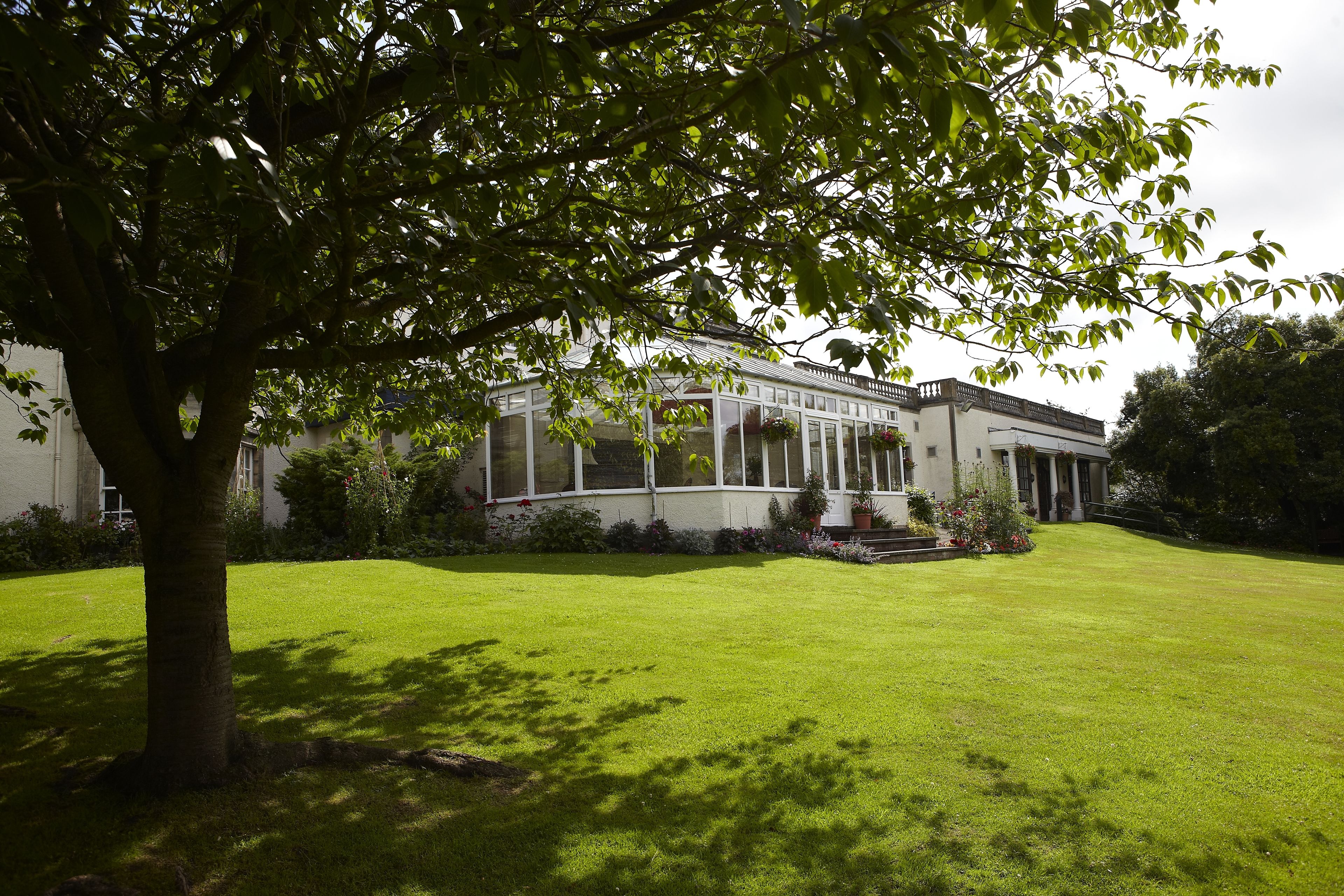 A modern building with a covered patio area, surrounded by a well-maintained lawn and trees.