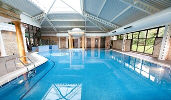 Una piscina techada, sillones reclinables de piscina