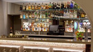 A bar area with multiple shelves of liquor bottles, a cash register, and a fruit bowl.
