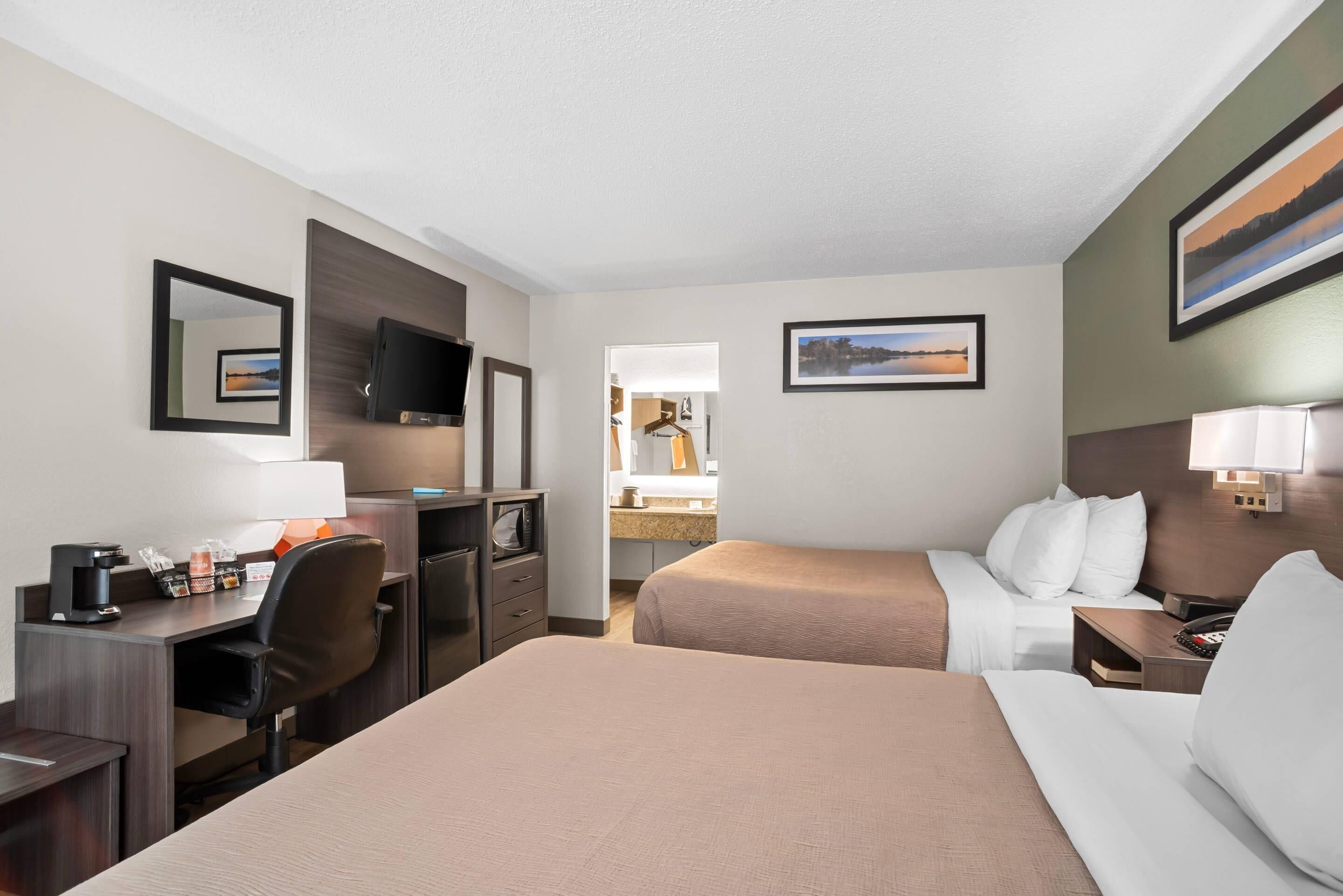Een hotelkamer met een bed, bureau, stoel en een televisie.