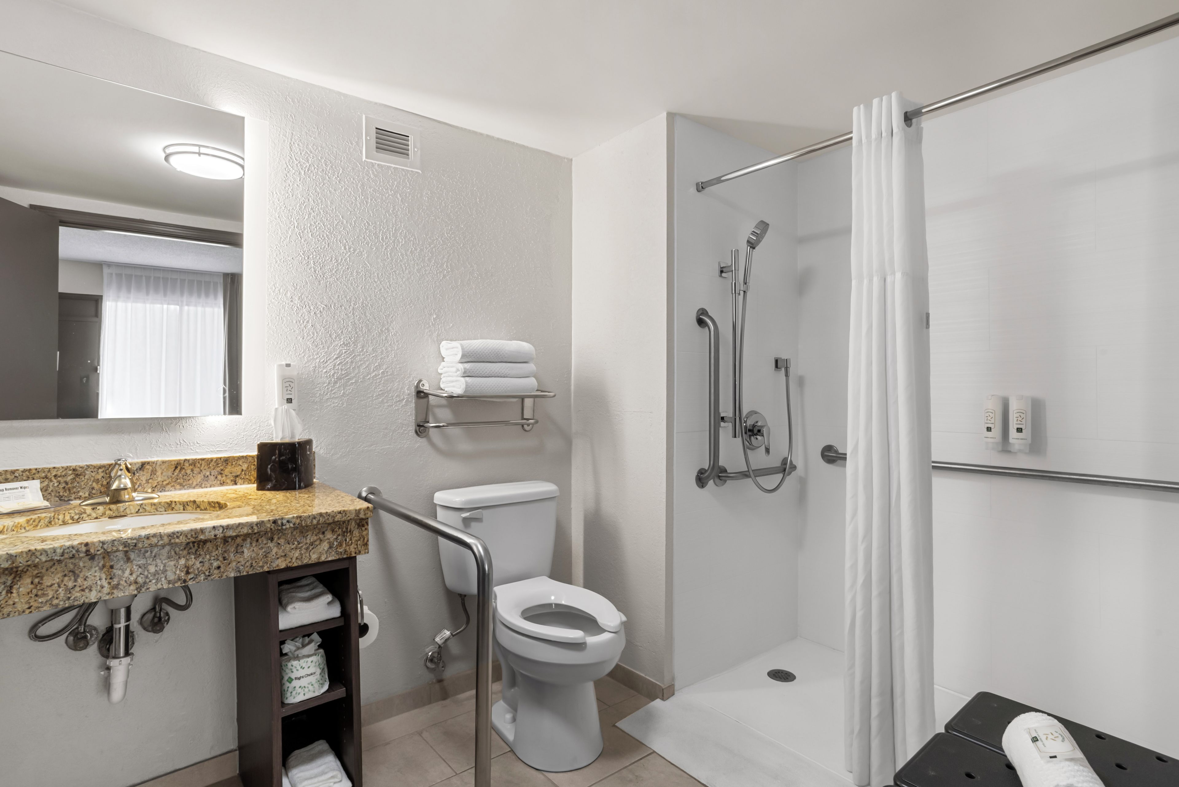 Une salle de bain moderne avec un lavabo sur un plan de travail en granit, des toilettes, une douche avec une porte en verre et un miroir.