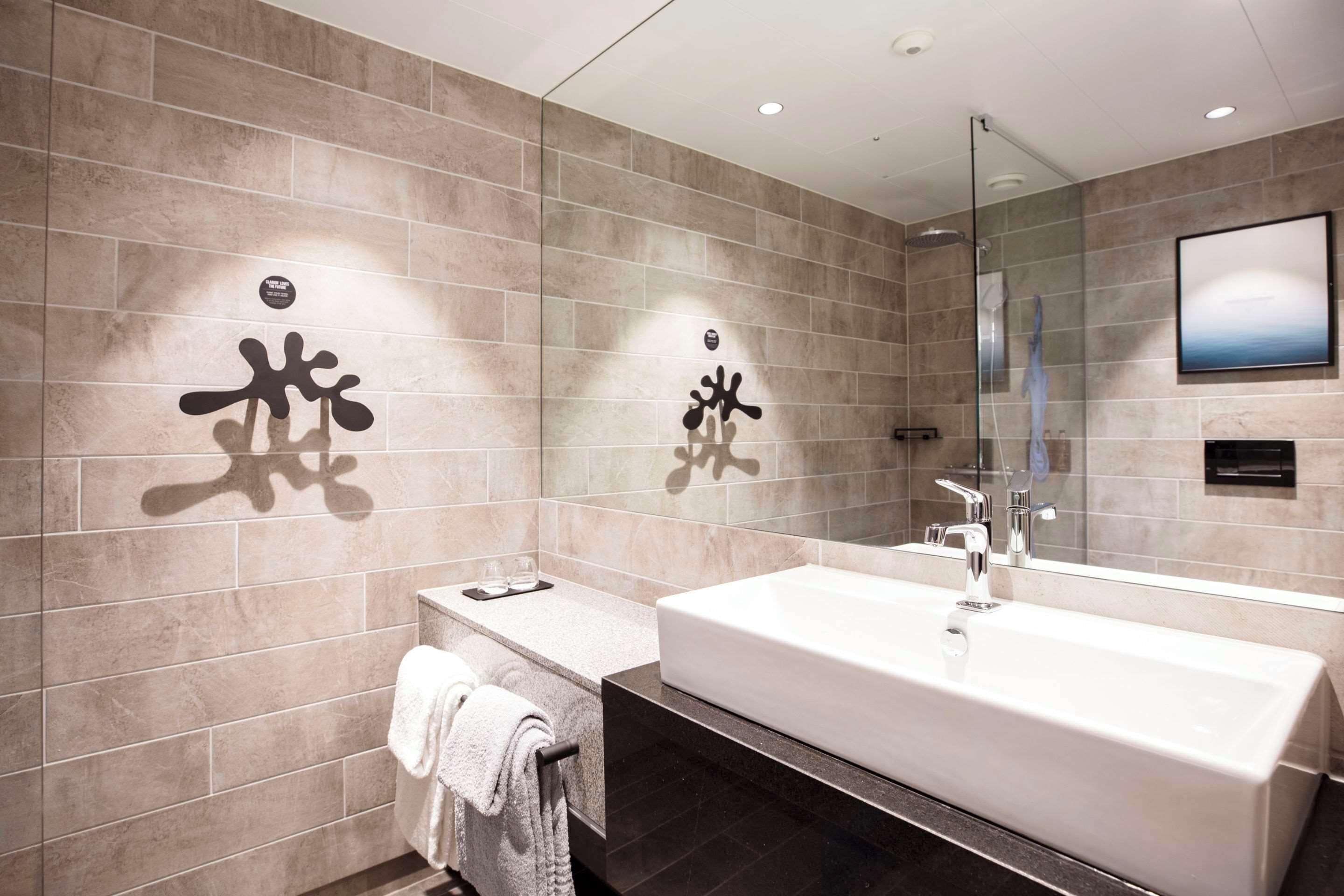Un baño moderno con un espejo grande, una bañera y un tocador con un perchero para toallas.