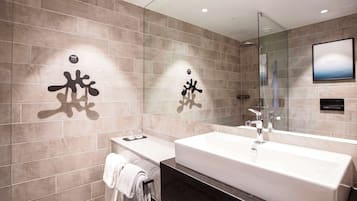 Un baño moderno con un espejo grande, una bañera y un tocador con un perchero para toallas.