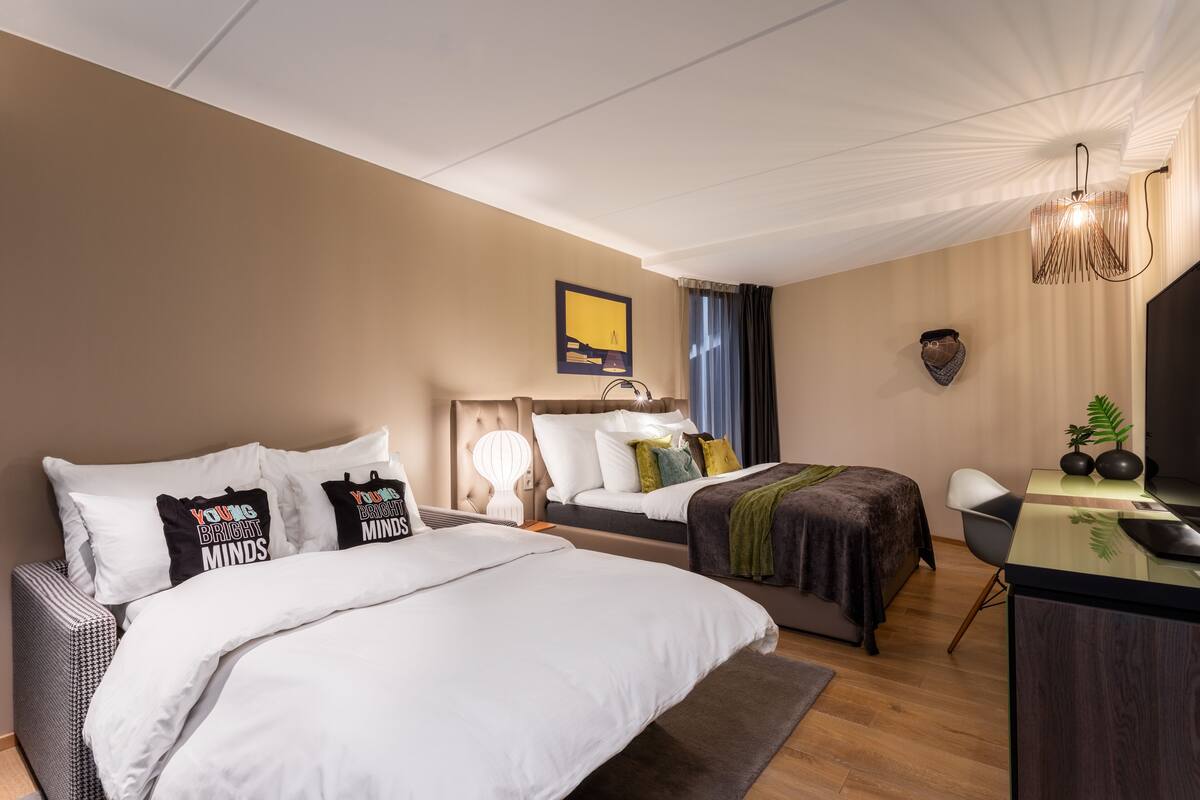 A hotel room with two beds, a desk, and a chair.