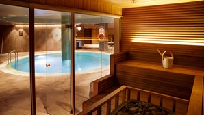 Uma área interna de piscina moderna com paredes de vidro, um deck de madeira e uma sauna.