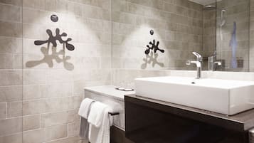A modern bathroom with a large mirror, a white sink, and a towel rack.