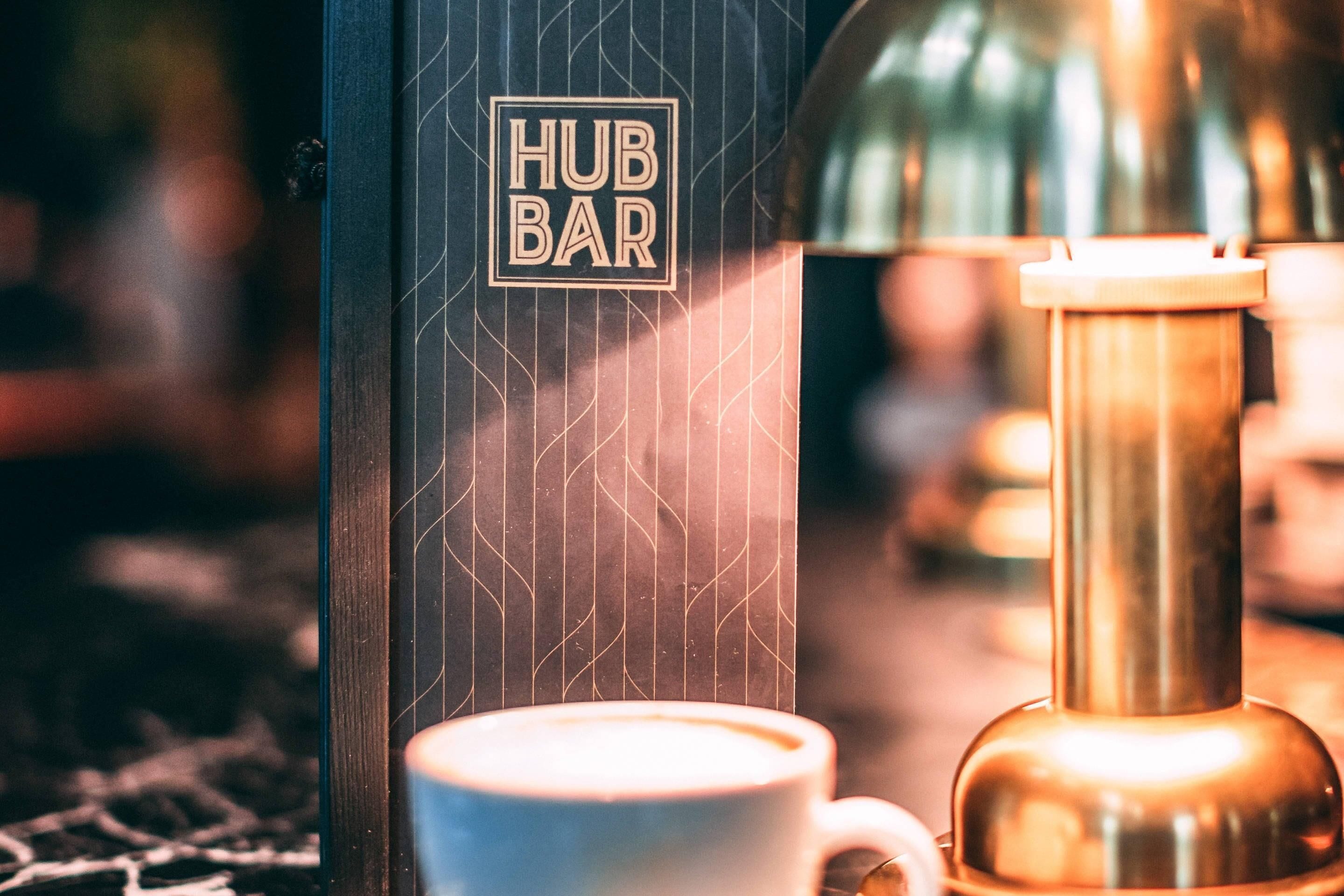 A coffee machine and a cup on a counter with a 'HUB BAR' sign.