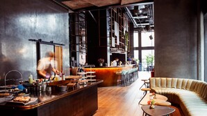 Uma área de bar moderna com balcão, banquetas e um espaço de estar com sofá e pufes.