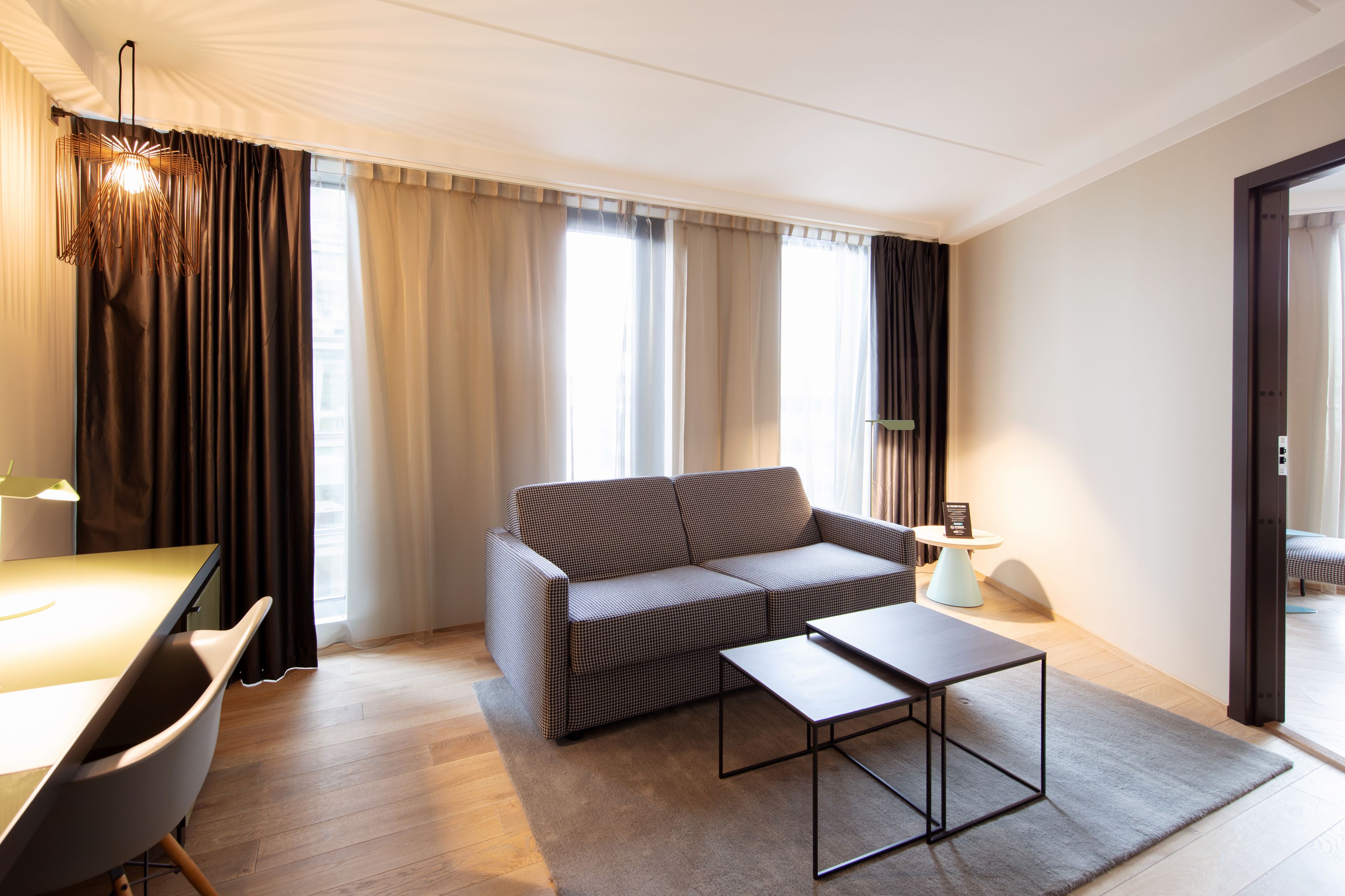 A modern living room with a sofa, a coffee table, and a dining area with a table and chairs.