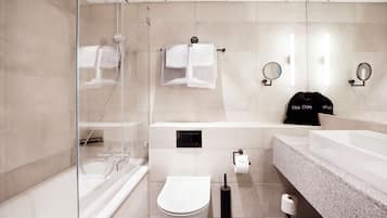 A modern bathroom with a glass shower enclosure, a white toilet, a bathtub, and a large sink with a granite countertop.
