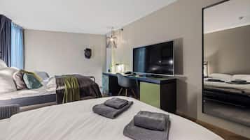 Habitación de hotel moderna con una cama grande, un escritorio, un televisor de pantalla plana y un espejo amplio.
