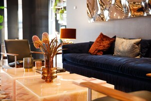 A modern living room with a blue sofa, a coffee table with a vase, and a lamp.