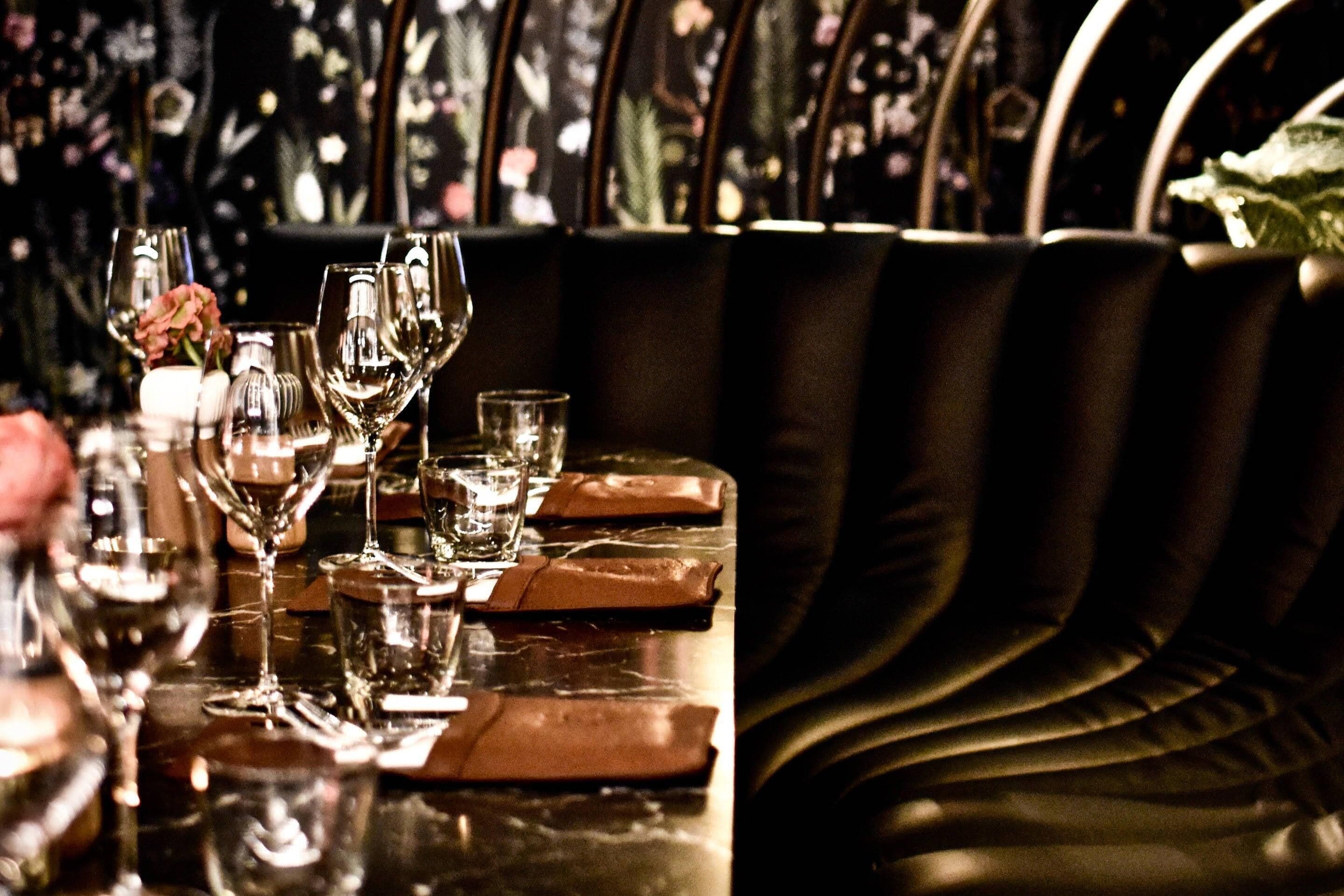 A bar area with a reflective surface, leather seating, and a floral wallpaper background.