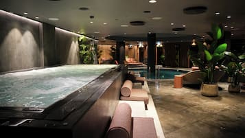 A spa area with a hot tub, seating, and a pool.