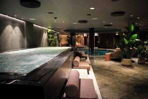 Un área de spa con un jacuzzi, asientos y una piscina.