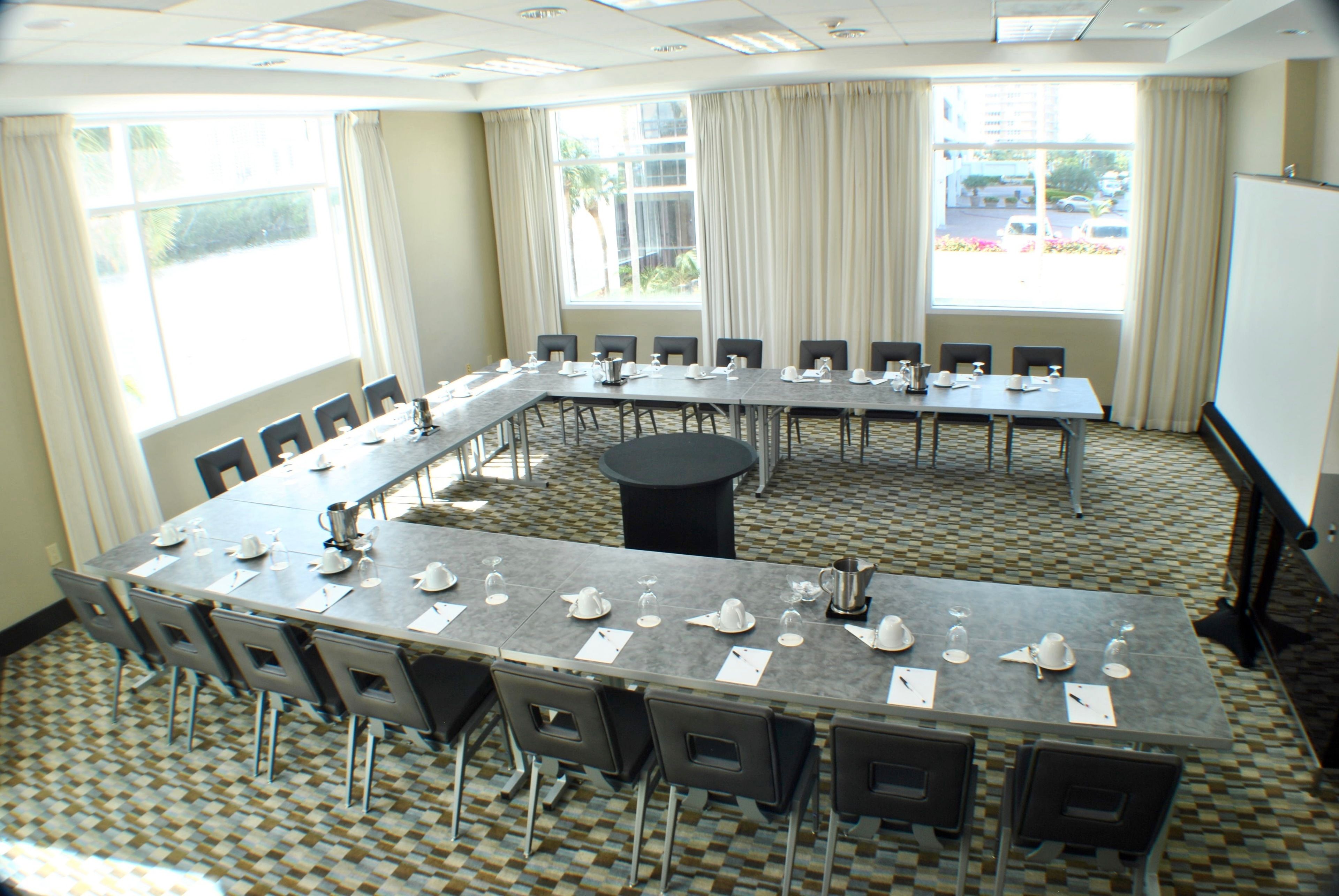 Un salón de conferencias con una larga mesa, sillas y una pantalla para proyector.