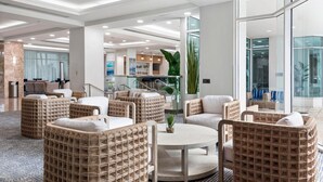 Un hall d’entrée moderne, doté de meubles en osier, d’une table ronde et d’une grande plante.
