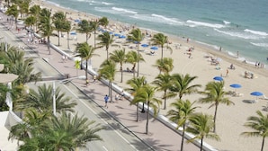 Une plage avec des palmiers, des parasols et des gens.