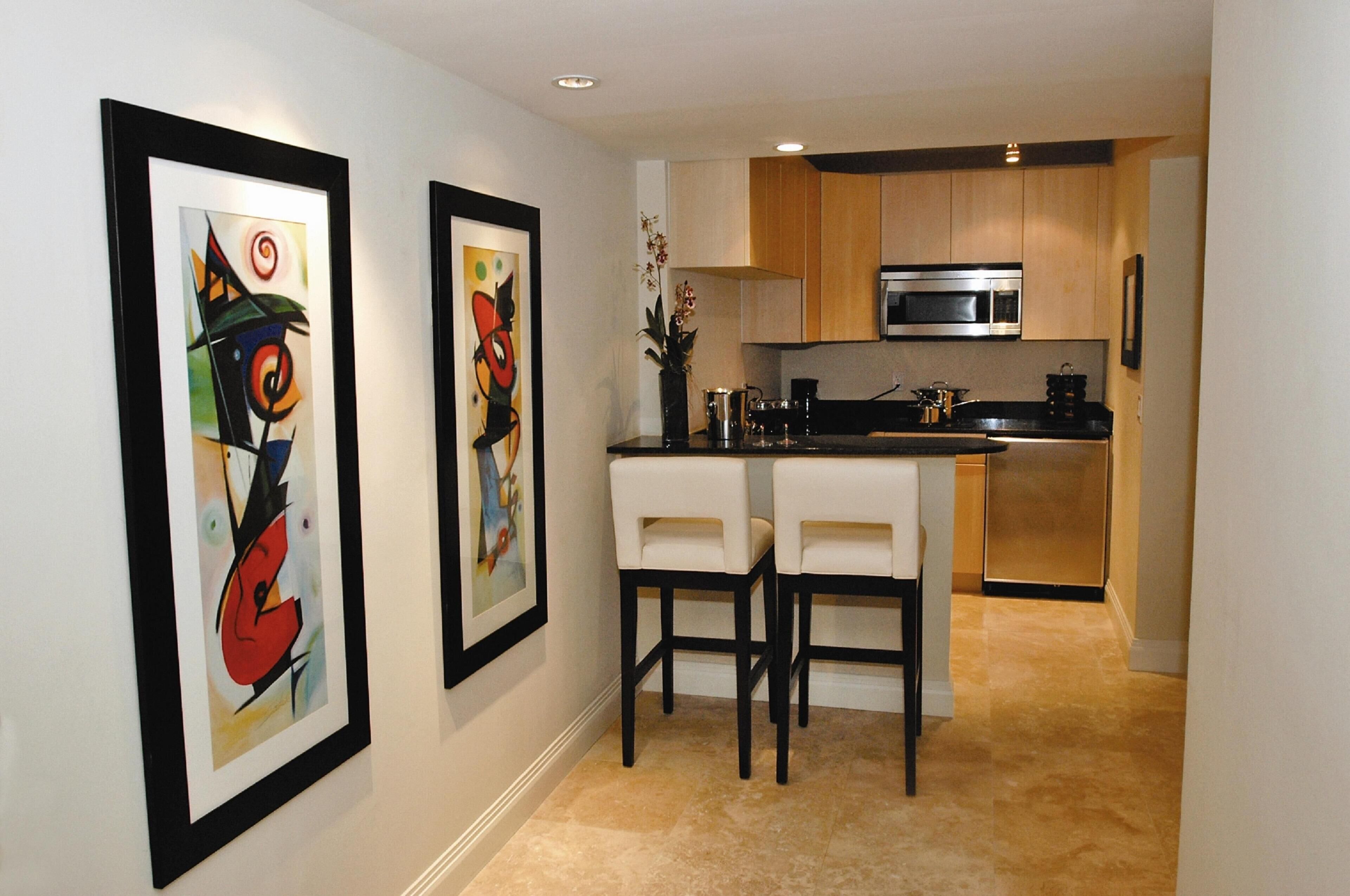 A modern kitchen with a microwave, stove, and two white bar stools.