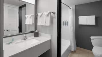 A modern bathroom with a white sink, a mirror, a bathtub, and a toilet.