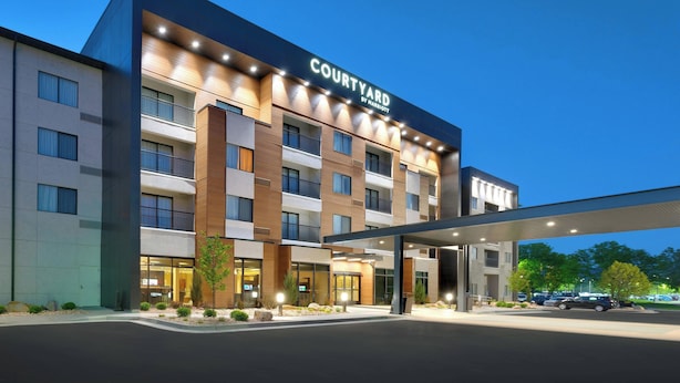 A multi-story hotel with a prominent 'Courtyard by Marriott' sign, a covered entrance, and a landscaped front yard.