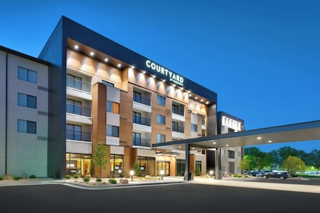 A multi-story hotel with a prominent 'Courtyard by Marriott' sign, a covered entrance, and a landscaped front yard.
