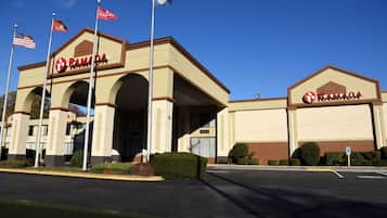 Classic hotel with a symmetrical facade, arched entryways, and a central entrance, set amidst well-manicured landscaping and a paved parking area.