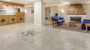 A hotel lobby with a reception desk, seating area, and a fireplace.