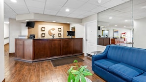 A reception area with a wooden reception desk, a blue sofa, and a large mirror.