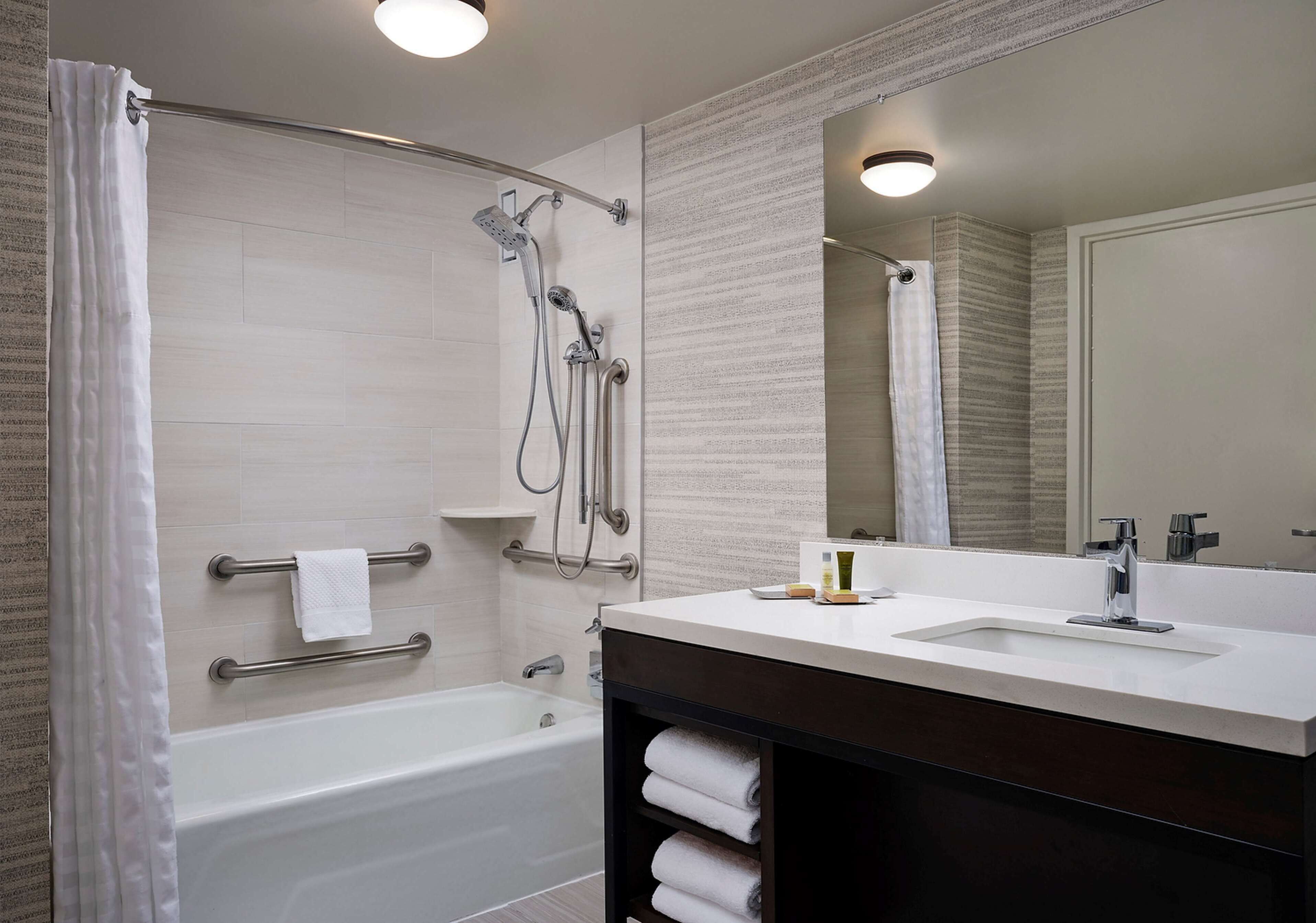 A modern bathroom with a bathtub, shower, and vanity with a sink.