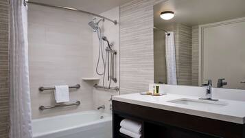 A modern bathroom with a bathtub, shower, and vanity with a sink.