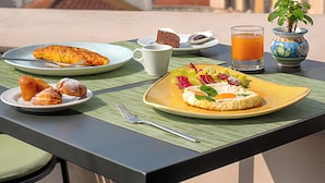 A table with breakfast items and a glass of orange juice, overlooking a cityscape with a prominent dome and buildings. - UNA Hotels Napoli (Naples)