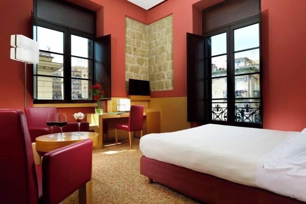Een hotelkamer met een bed, een bureau, een stoel en een televisie.