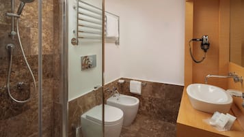 Un bagno moderno con box doccia in vetro, un bidet, un water, un lavandino con mobile e un porta asciugamani.